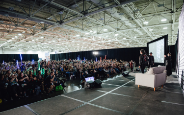 pictured is a large audience from the stage perspective, with some members of the audience holding up lightsabers.