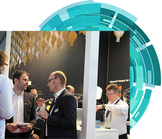 Attendees at an exhibition standing around a table, participating in conversation and sharing ideas