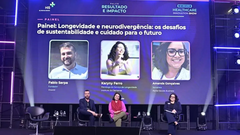 Painel sobre longevidade e neurodivergência no evento Healthcare Innovation Show (HIS), com os palestrantes Fabio Serpa, Karyny Ferro e Amanda Gonçalves no palco Resultado e Impacto.