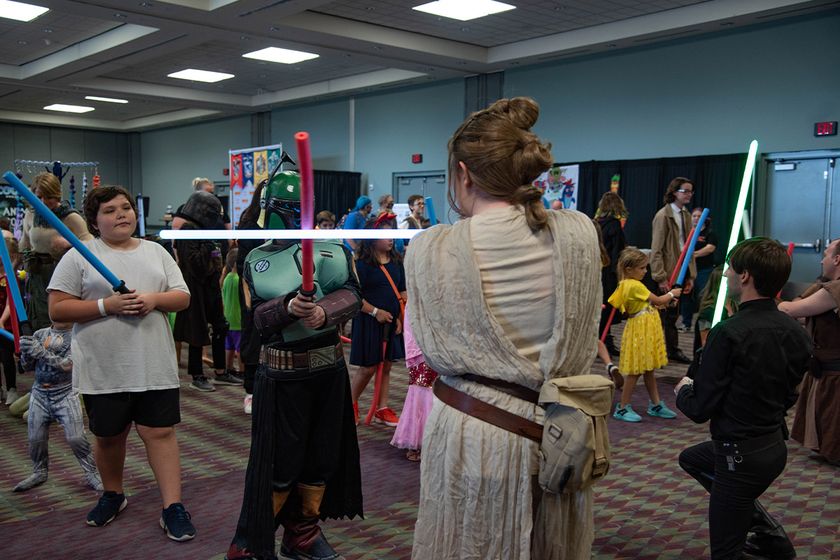 A group of young attendees learn to use a lightsaber