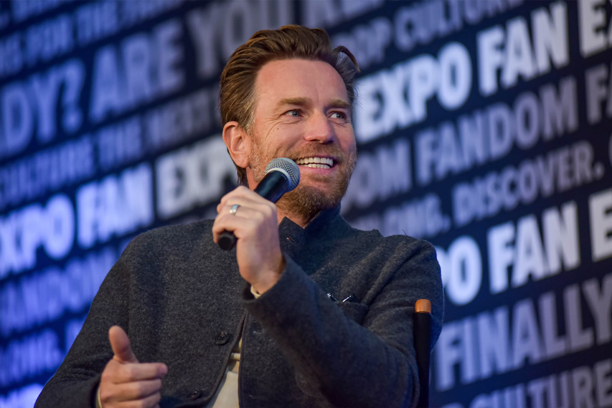 Ewan McGregor smiles holding a microphone on stage