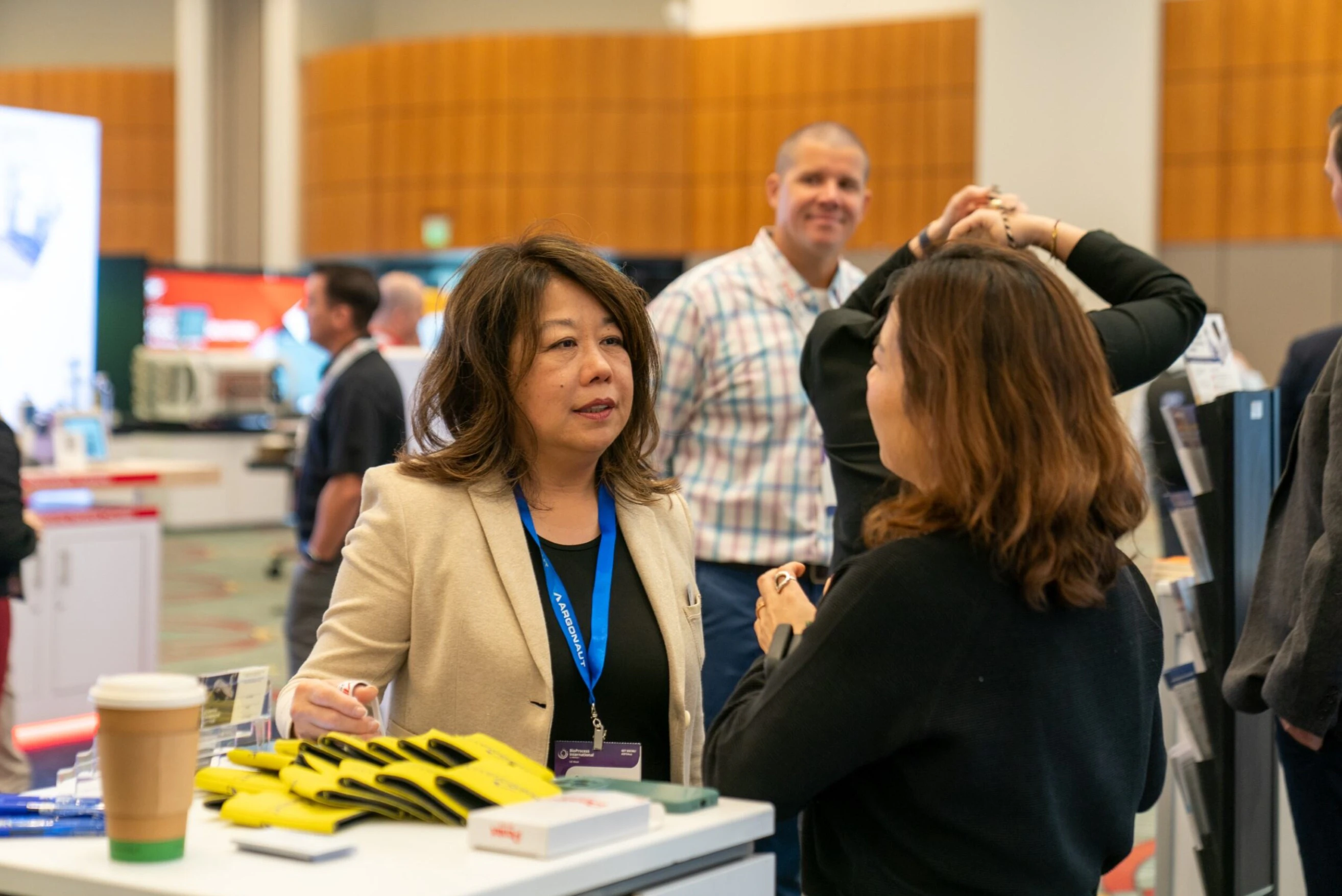 Bioprocessing attendees at BPI West in discussion at a table in the exhibition hall.