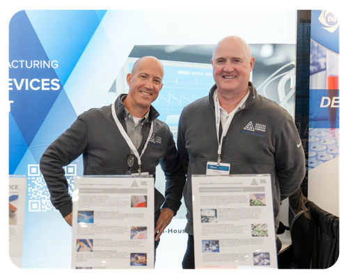 Two men standing side by side at an exhibit, engaged in conversation and observing the displayed items.