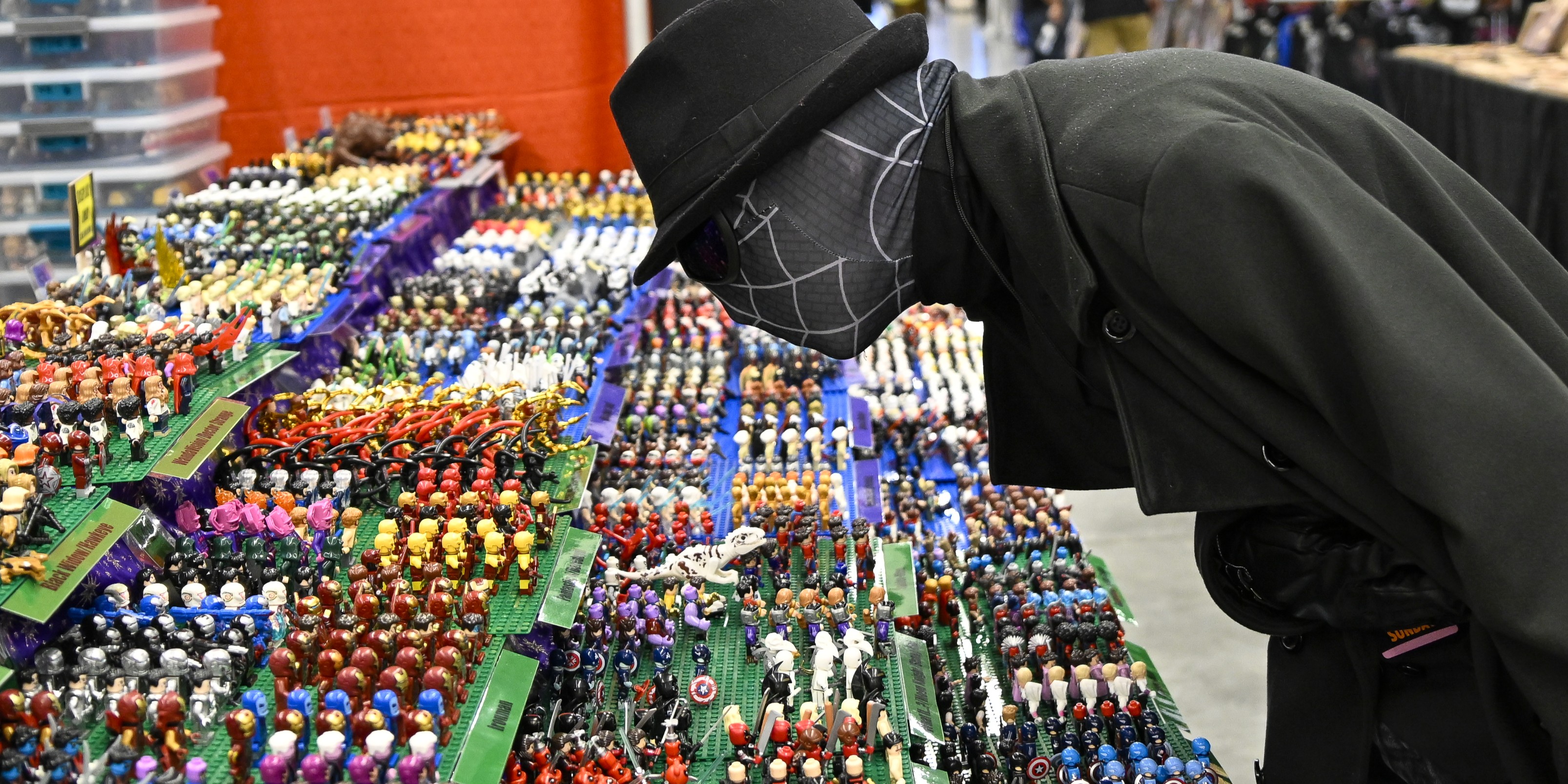 An attendee browses colorful pins and collectibles at a vendor booth on the FAN EXPO Cleveland show floor. Rows of merchandise fill the display as the fan examines items up close.
