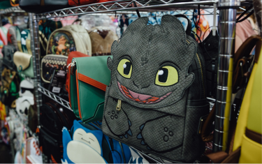 A black Toothless backpack (from How to Train Your Dragon) sitting on a shelf.