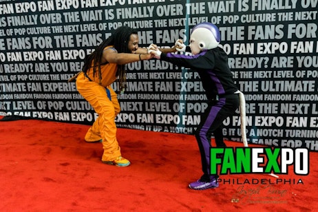 Goku and Frieza cosplayers posing in a fight position on the red carpet