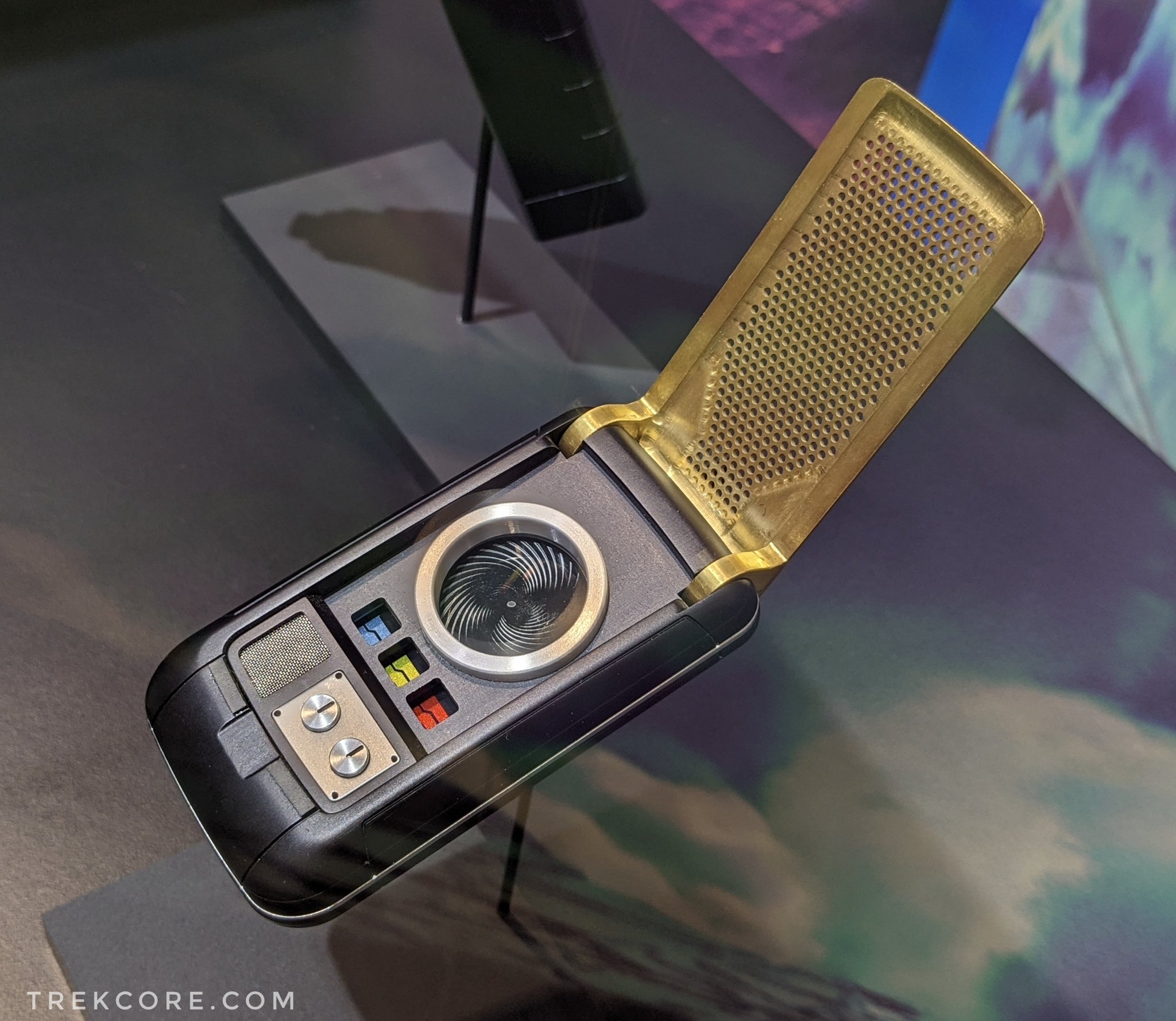 A Starfleet communicator open, and on display over a Star Trek projection of outer space