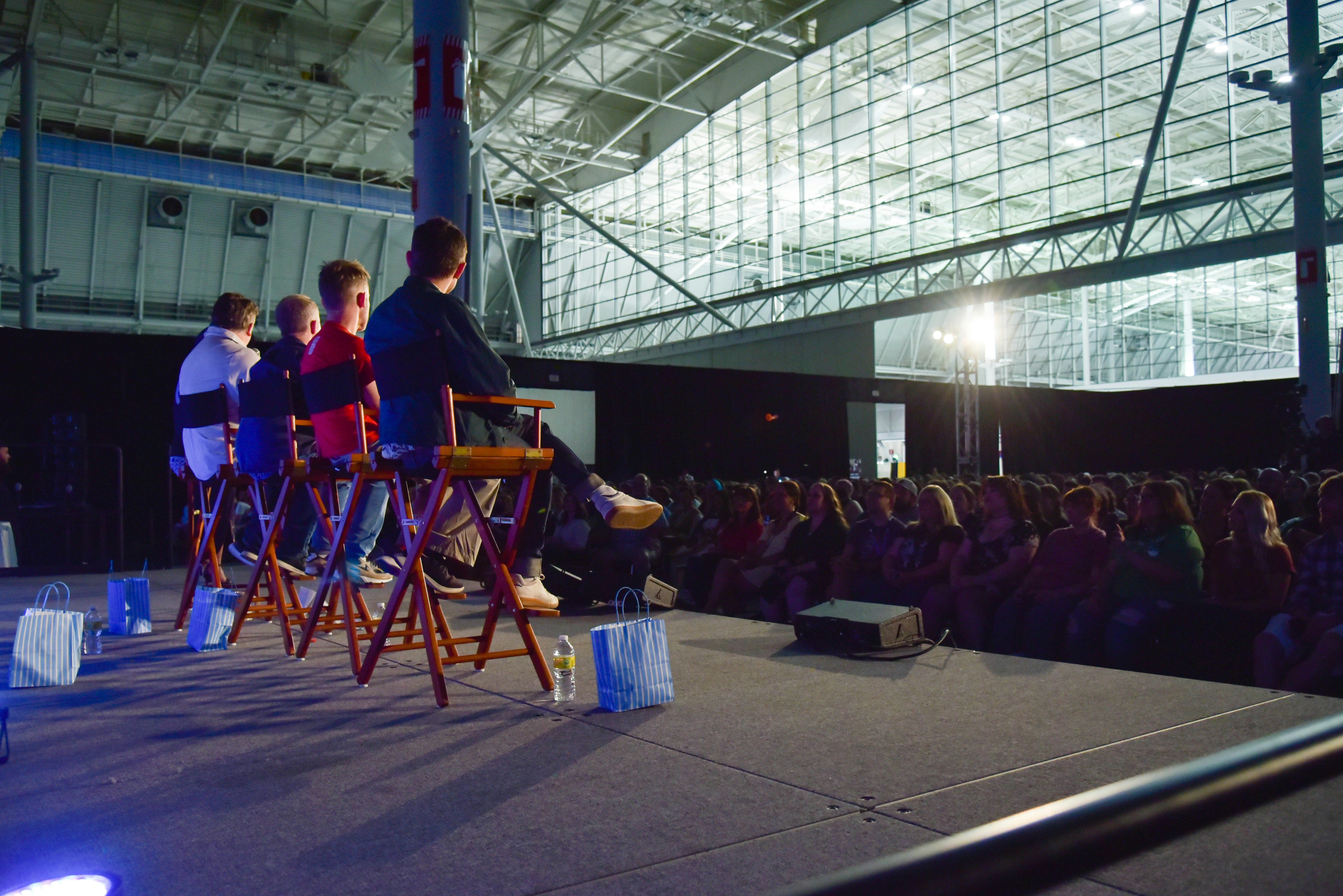 A shot of the four Hobbits (Elijah Wood, Dominic Monaghan, Billy Boyd, and Sean Astin) seated at their panel, overlooking the crowd.