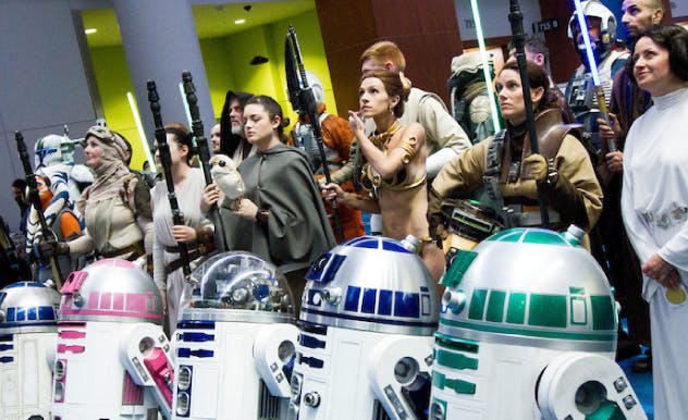 rainbow of R2D2 droids posing with Star Wars cosplayers in lineup