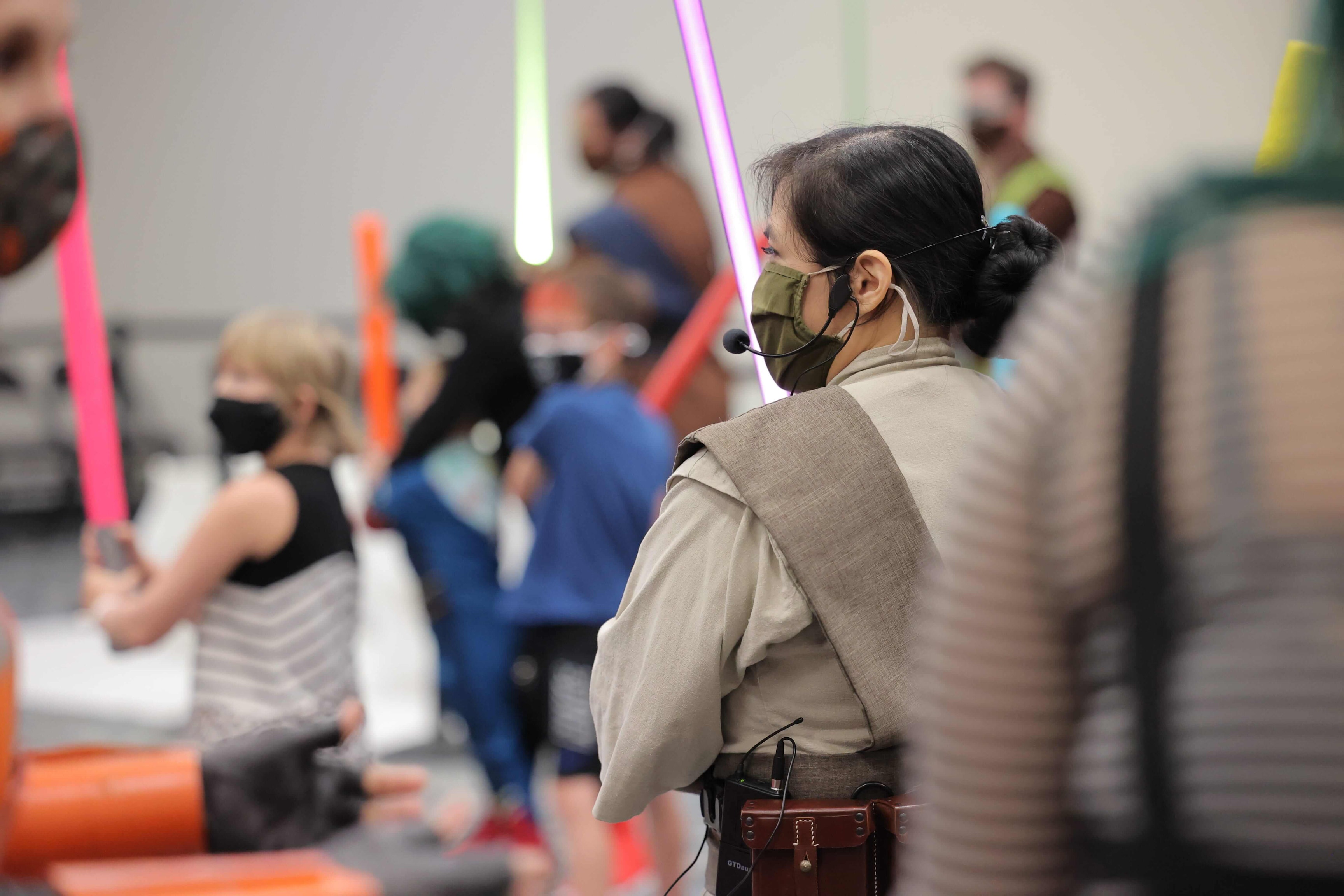 A group of fans all stand in attack ready pose with their lightsabers glowing