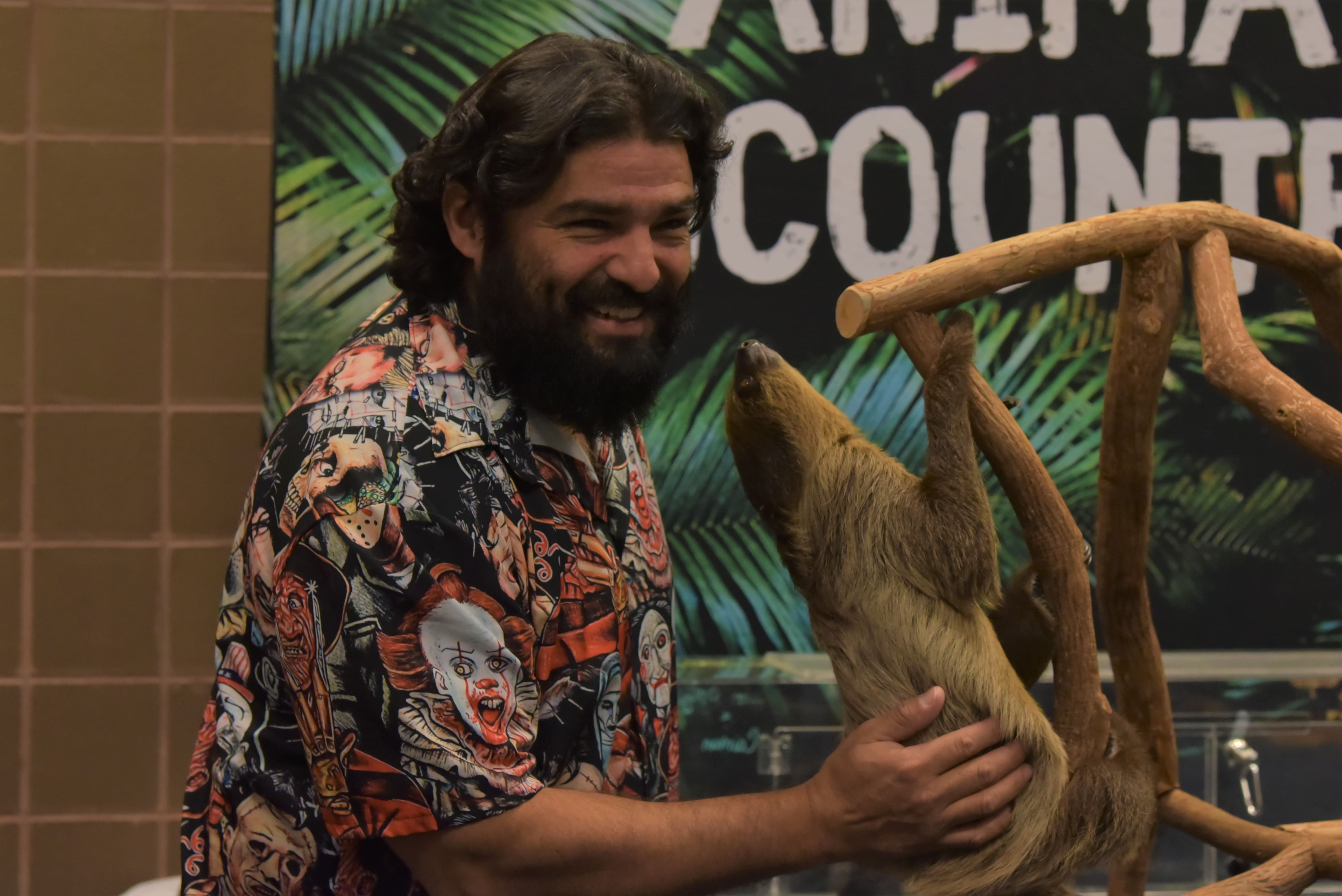 One of the handlers for the Animal Encounters activation in the Family Zone petting a sloth.