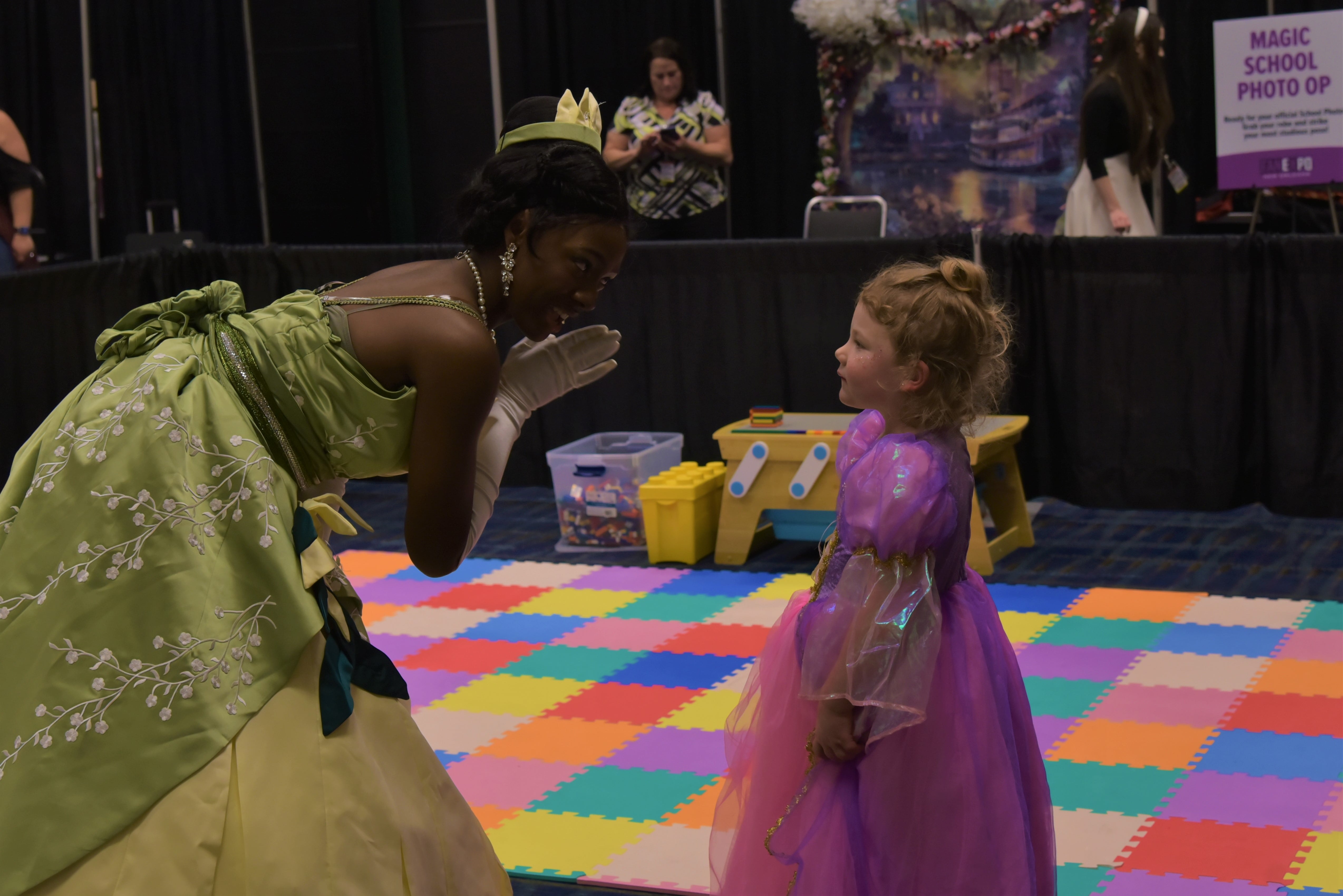Princess Tiana speaking to a young girl cosplaying as Rapunzel in the Family Zone.