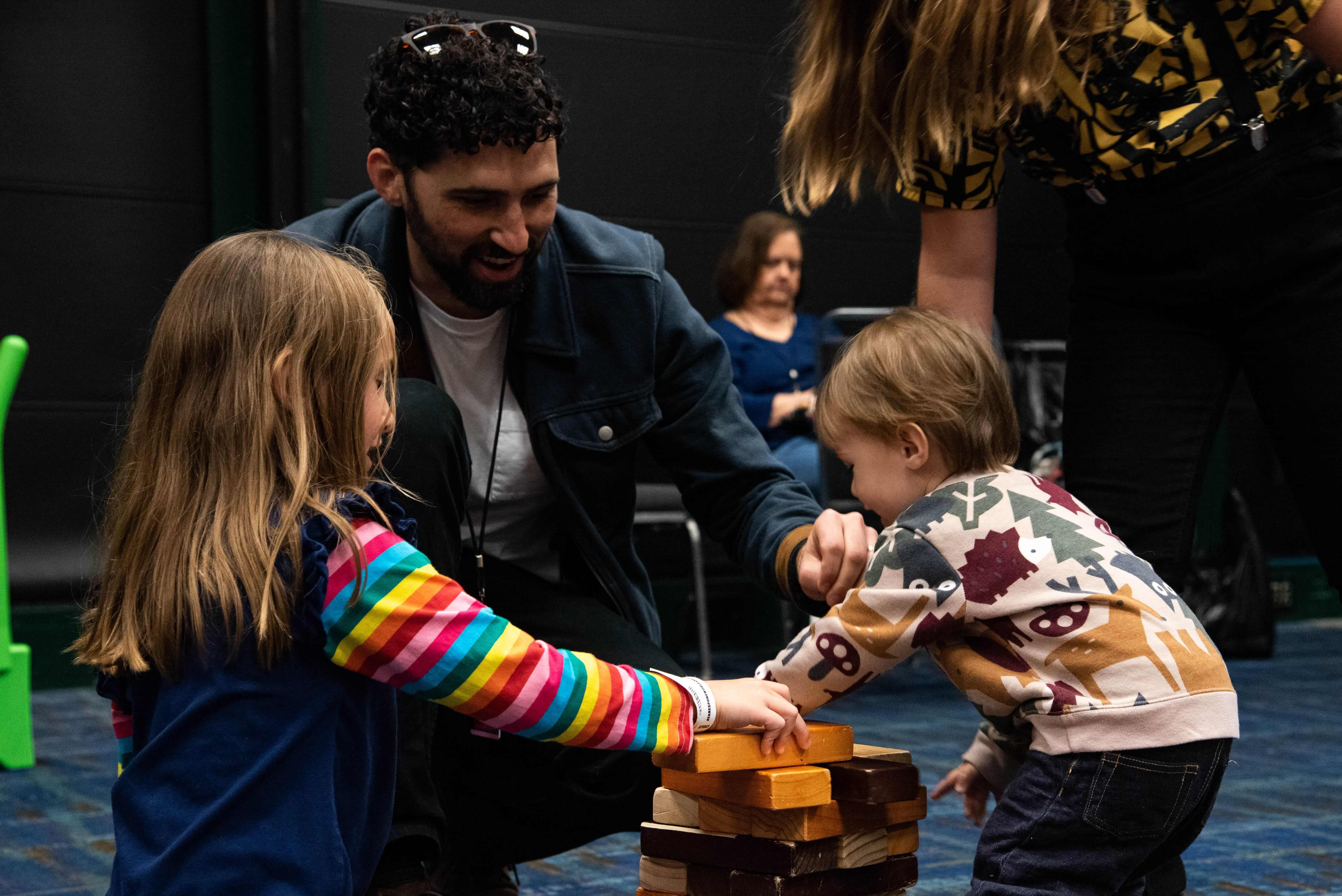 A family playing together with big Jenga blocks in the Family Zone.