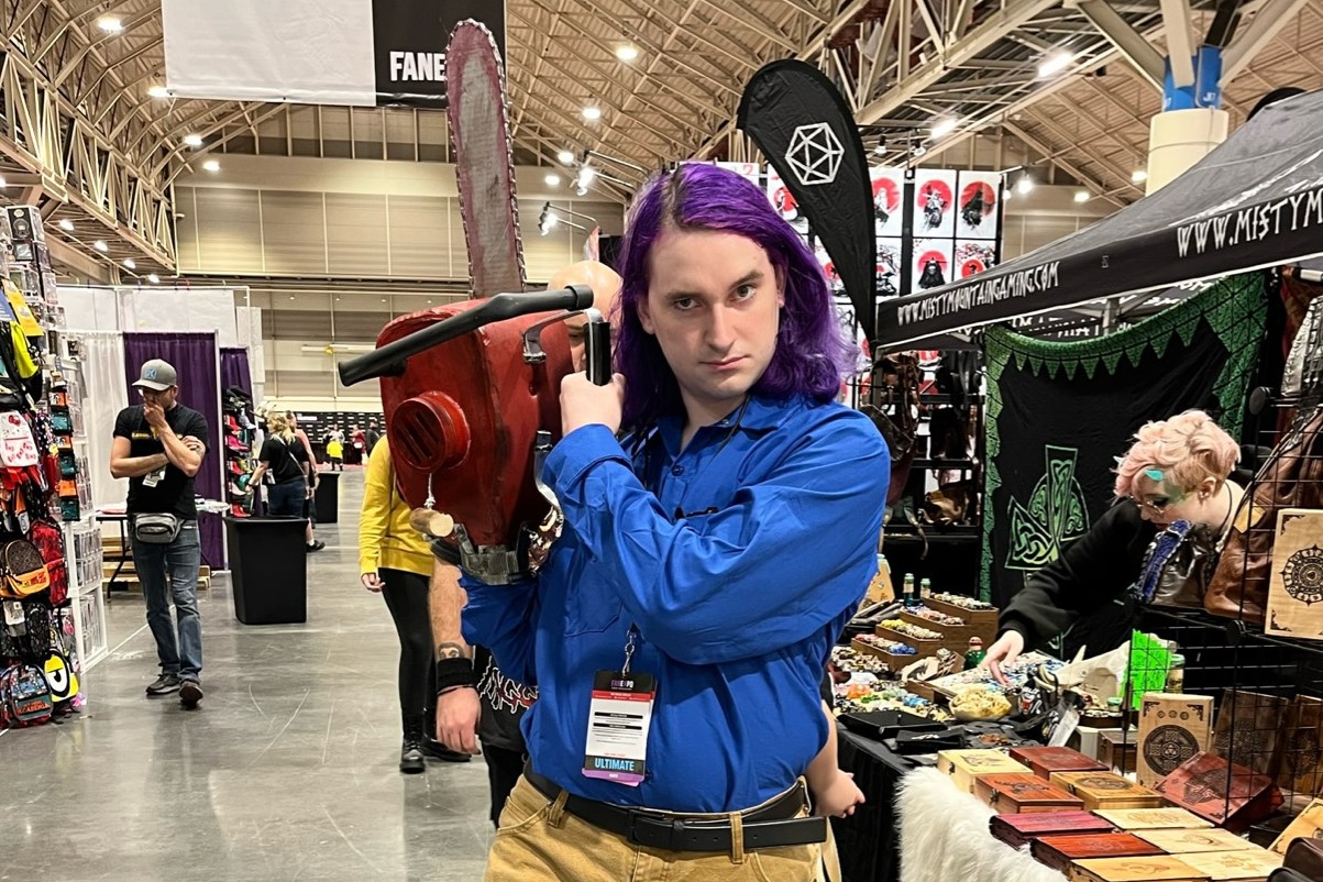 An Ash Williams cosplayer posing for the camera with their chainsaw hand.
