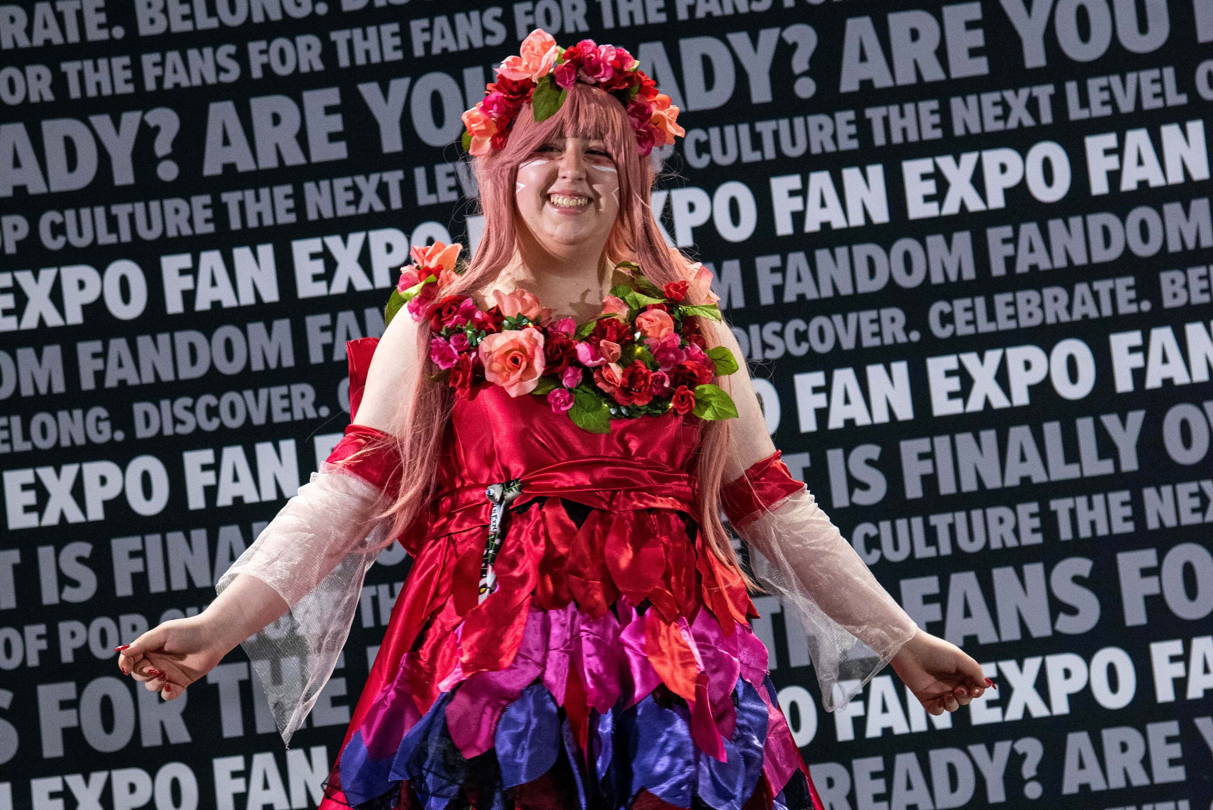 One of the Cosplay Craftsmanship Cup contestants on stage, smiling as they show off their cosplay.