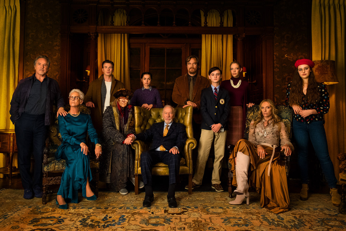 The entire cast of Knives Out standing in a room looking at the camera for a family portrait