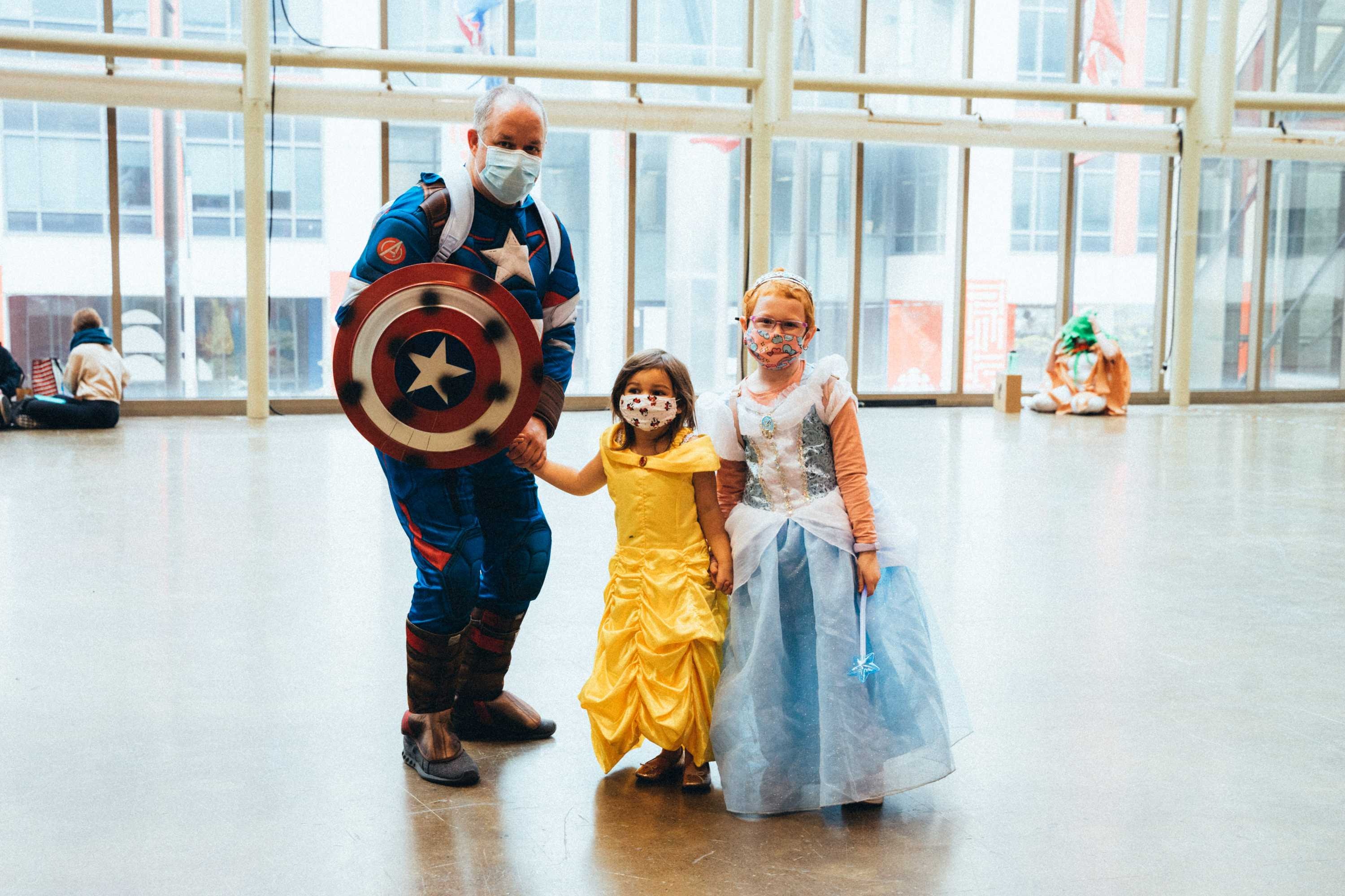 A family of Cosplayers pose dressed as Belle, Cinderella and Captain America