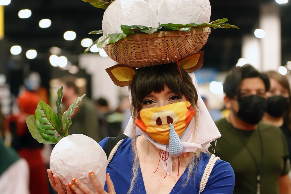 A Daisy Mae cosplayer poses holding a large turnip in her hands