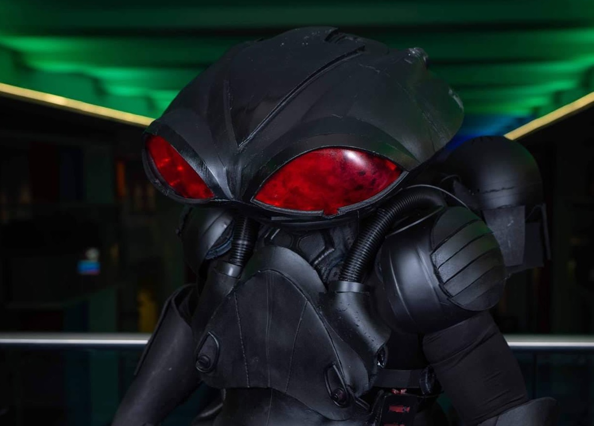 FRANK CORACI AS MANTA FROM AQUAMAN WITH BIG RED EYES AND A GREEN BACKGROUND