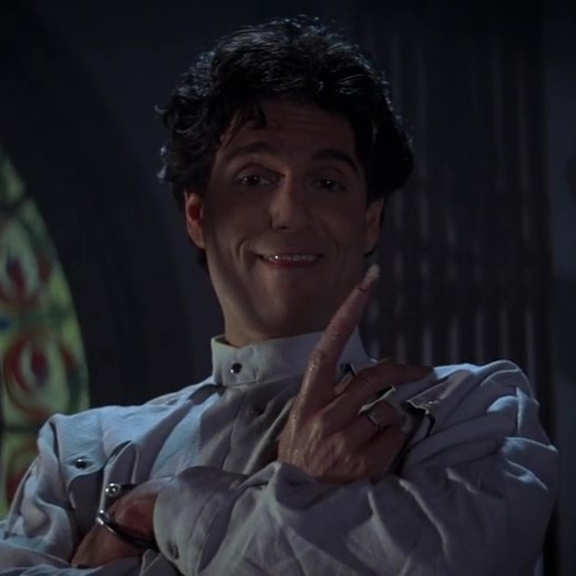 Chris Sarandon wearing all white. He is smiling, with a menacing look in his eye..