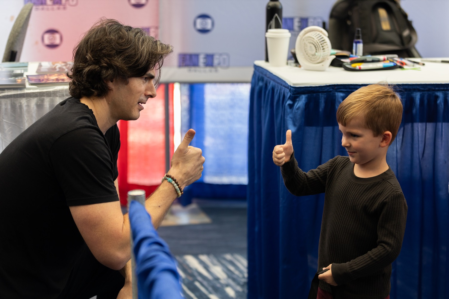 Actor Brandon Routh gives a thumbs-up to a young boy, who enthusiastically returns the gesture in a bonding moment at FAN EXPO.