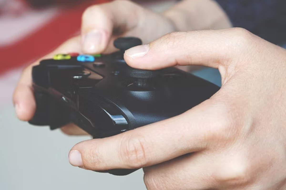 A persons hands hold a black Xbox controller