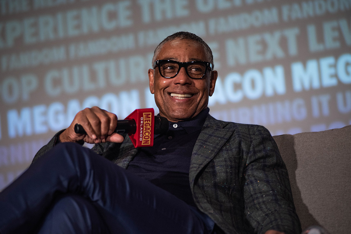 Giancarlo Esposito smiles big while holding a microphone