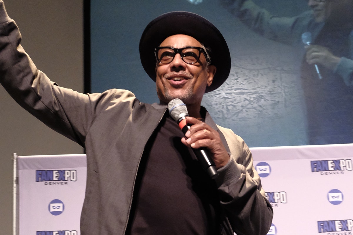 Giancarlo Esposito smiles as he speaks into a microphone on stage