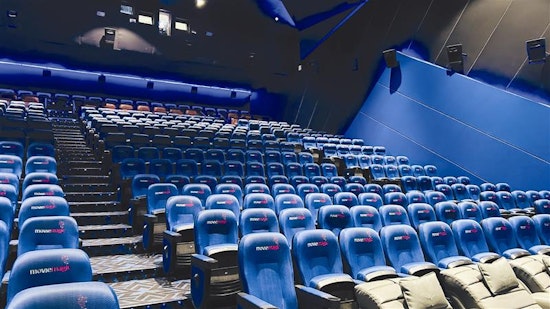 Modern movie theater auditorium with tiered blue reclining seats, atmospheric lighting, and large projection screen"