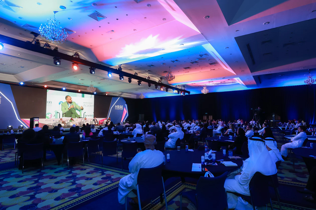 Conference attendees listening to a speaker on stage at HRSE Summit.