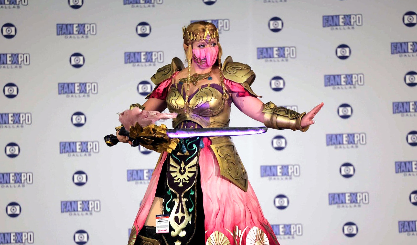 A cosplayer dressed as Princess Zelda from the Legend of Zelda games poses on the red carpet with her sword