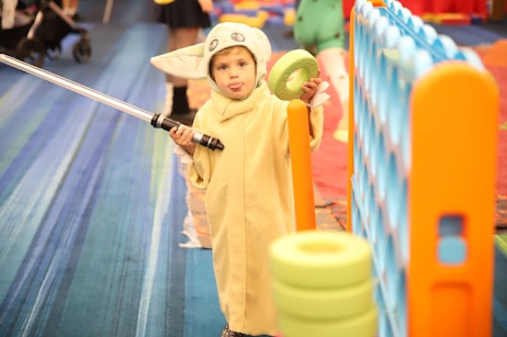 Cute child cosplaying grogu in the family zone