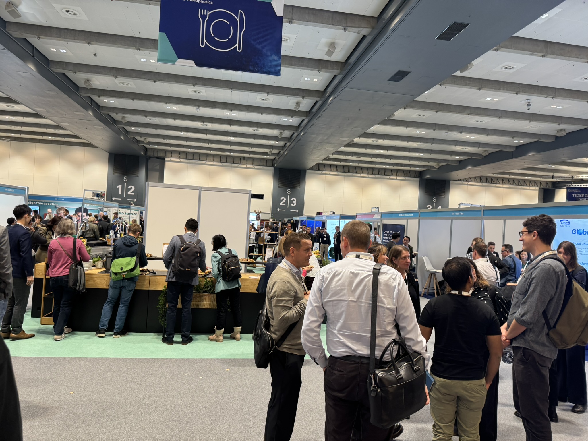 Large exhibition hall with attendees networking, all in smartwear.