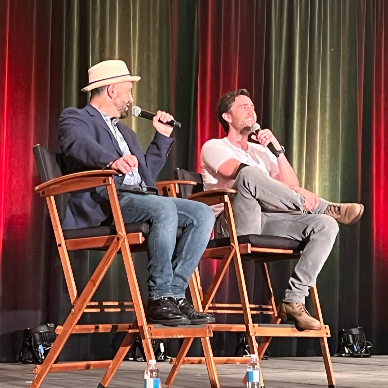 He is sitting on a panel with the director chairs. It looks like he is listening to a question.