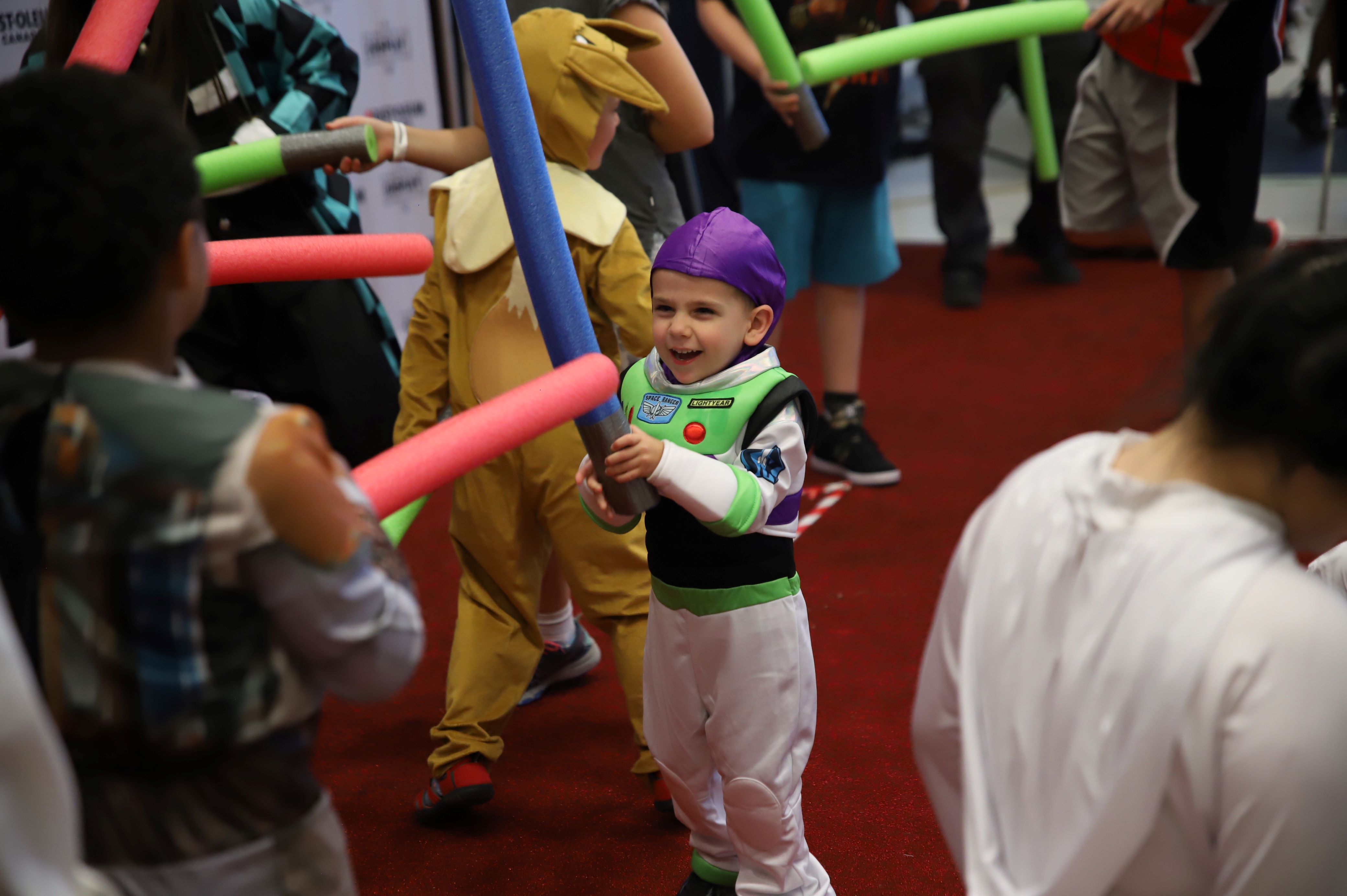 CHILD COSPLAYING BUZZ LIGHTYEAR SMILES DURING THE LIGHTSABER BATTLE