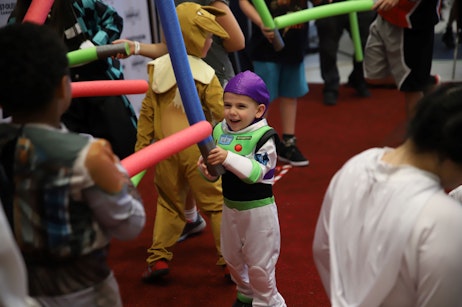 Child cosplaying Buzz Lightyear is smiling during the lightsaber battle