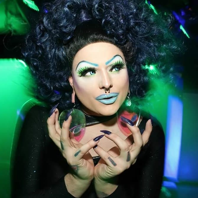 VEP in a black wig with long black nails and a sinister look