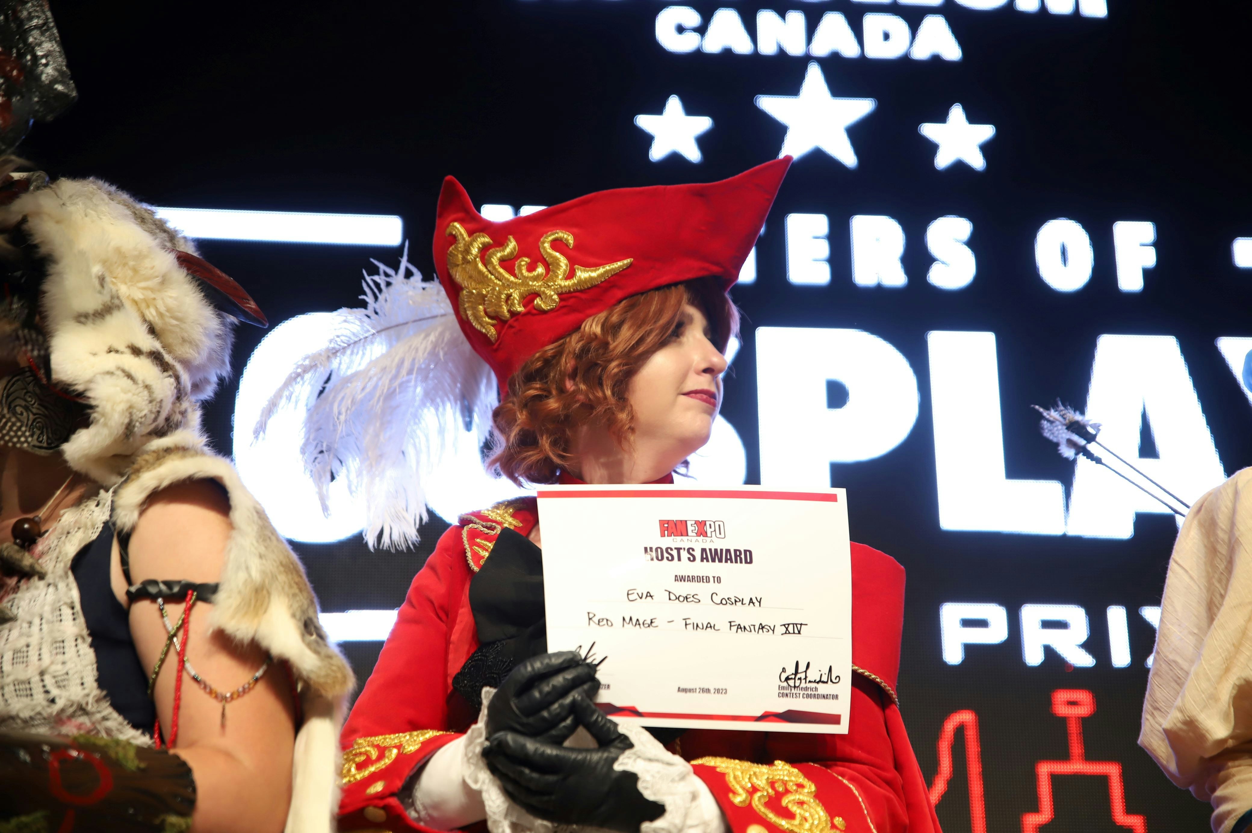 cosplayer poses with certificate on stage