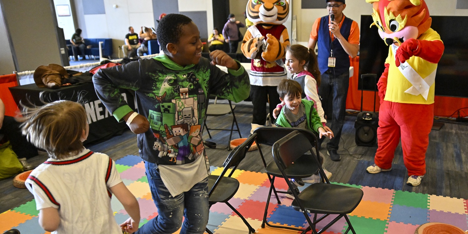 Children play an interactive video game in the Kids’ Zone at FAN EXPO Cleveland. The kids stand in front of a large screen while wearing headsets, moving and laughing during a hands-on gaming activity.