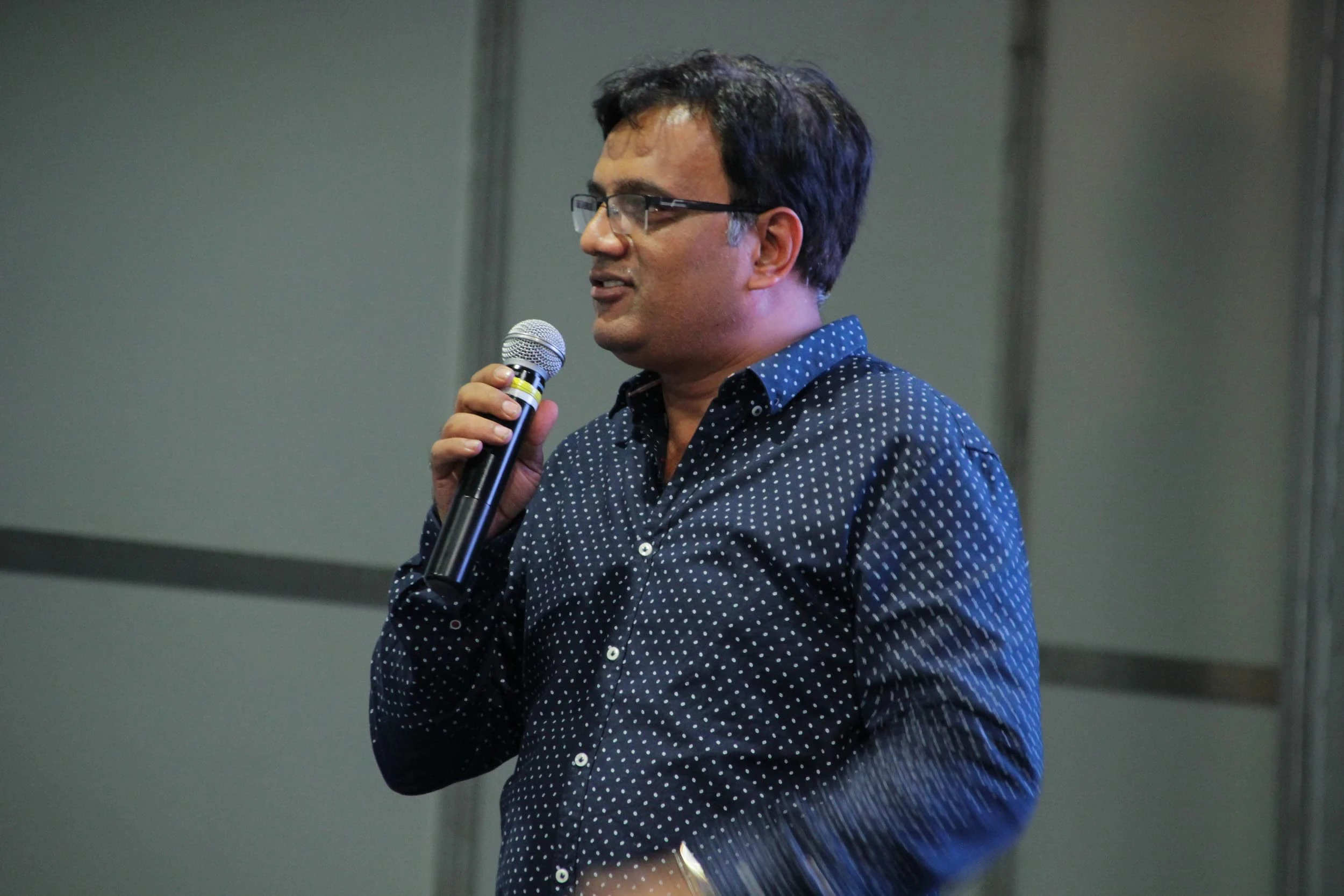 Man wearing glasses speaking into a microphone at the IRAA Palm Awards