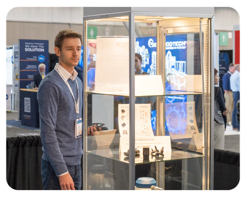 A man is positioned in front of a display case, looking at inside, engaged in the presentation.