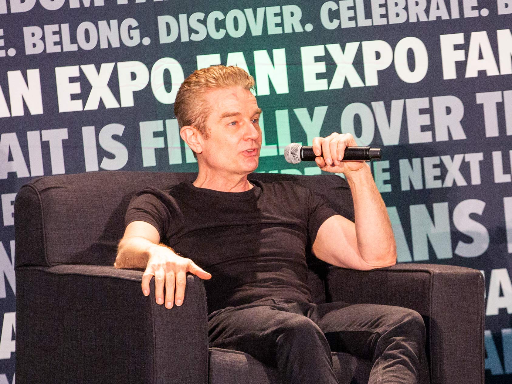 James Marsters on stage holding a microphone