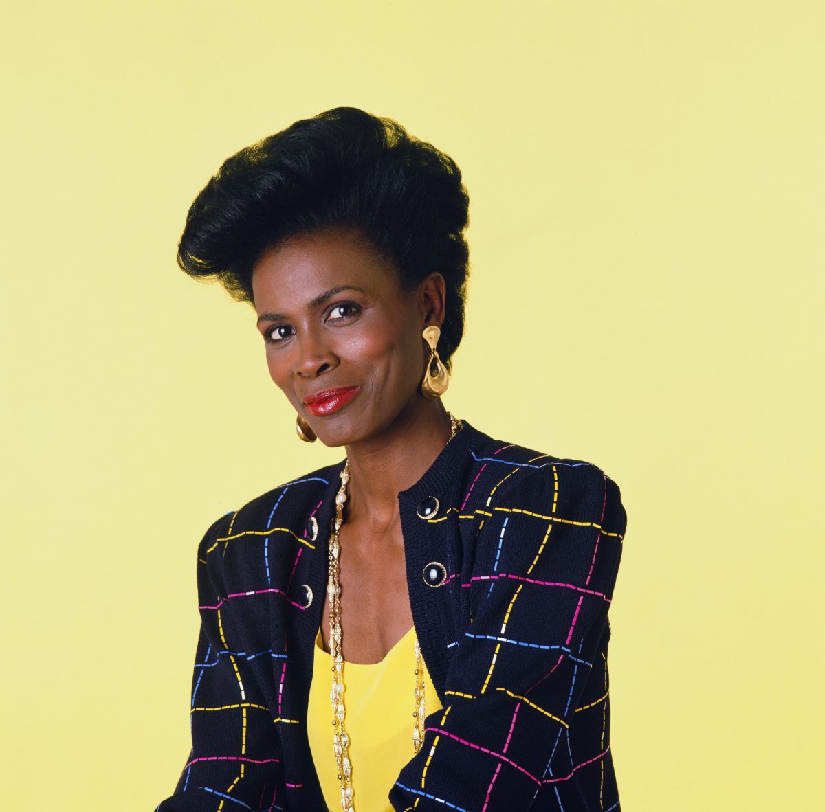Aunt Viv from Fresh Prince of Bel Air on a solid yellow background wearing a yellow shirt