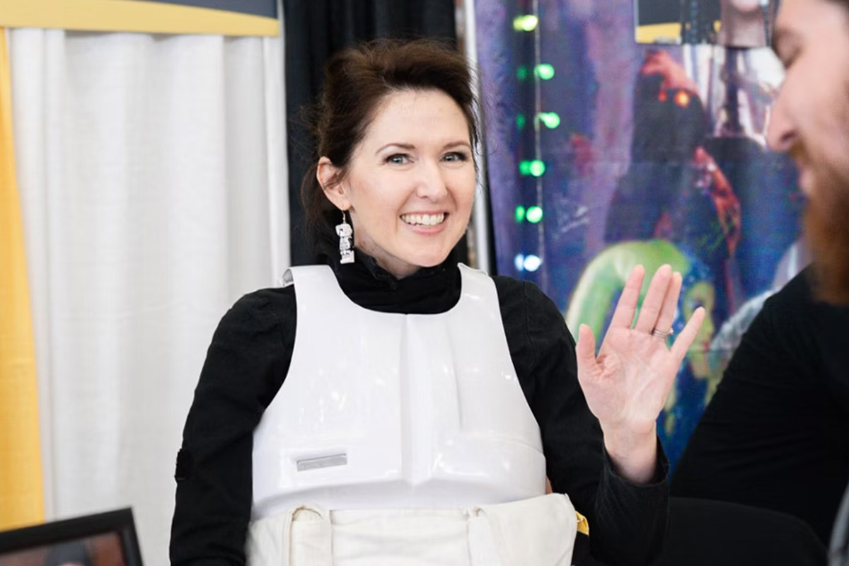 Cosplayer Jen Markham waves at the camera, smiling