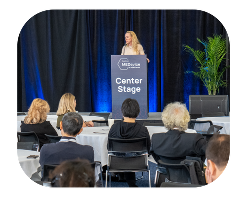 A woman stands at a podium, delivering a presentation to an audience at a professional conference