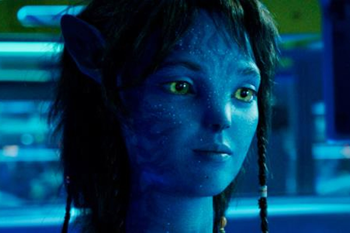 Kiri stands with a small smile on her face looking at something off camera