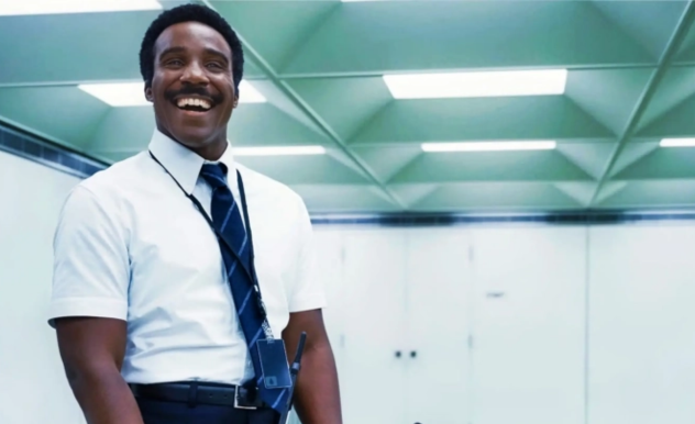 Seth stands, smiling widely, very straight-backed and confident.