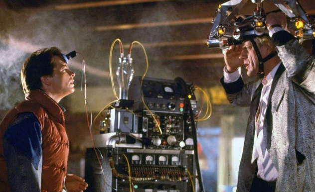 Wearing his own version of protective gear - Doc stares at Marty, who stares back in awe. A small plunger-like device is stuck to Marty's forehead.