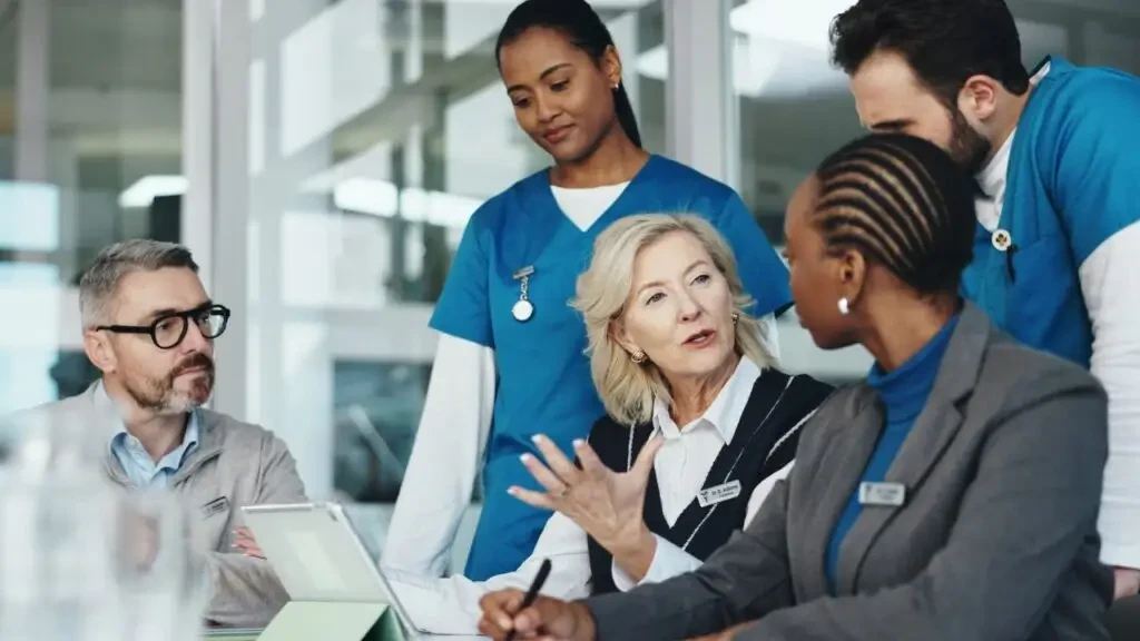 Equipe multidisciplinar e gestores hospitalares reunidos a discutir estratégias e formação de liderança na saúde.