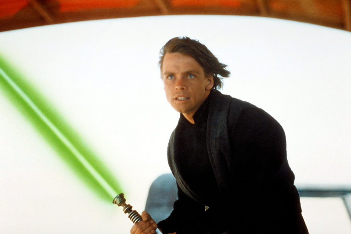 Luke Skywalker with black robes on holding an ignited green lightsaber on Tattooine